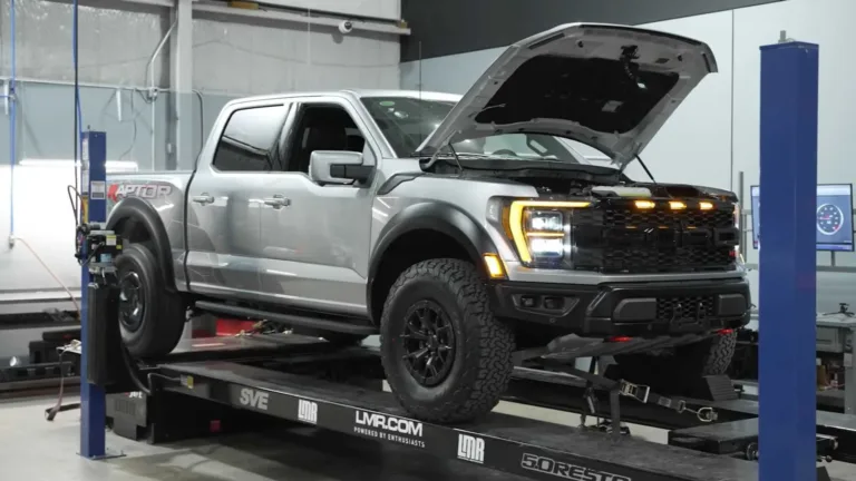 Ford F-150 Raptor R gris con el capó abierto sobre un banco de pruebas de potencia en un taller