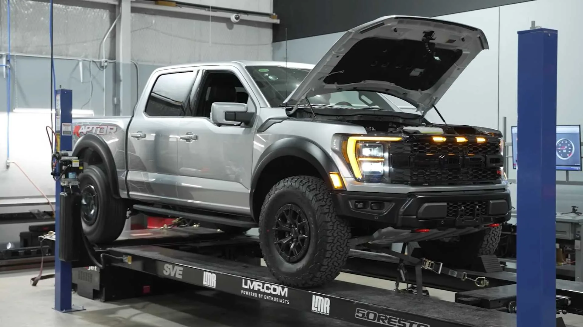 Ford F-150 Raptor R gris con el capó abierto sobre un banco de pruebas de potencia en un taller