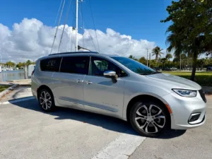 Chrysler Pacifica Pinnacle plateada de perfil, estacionada frente a una marina con veleros
