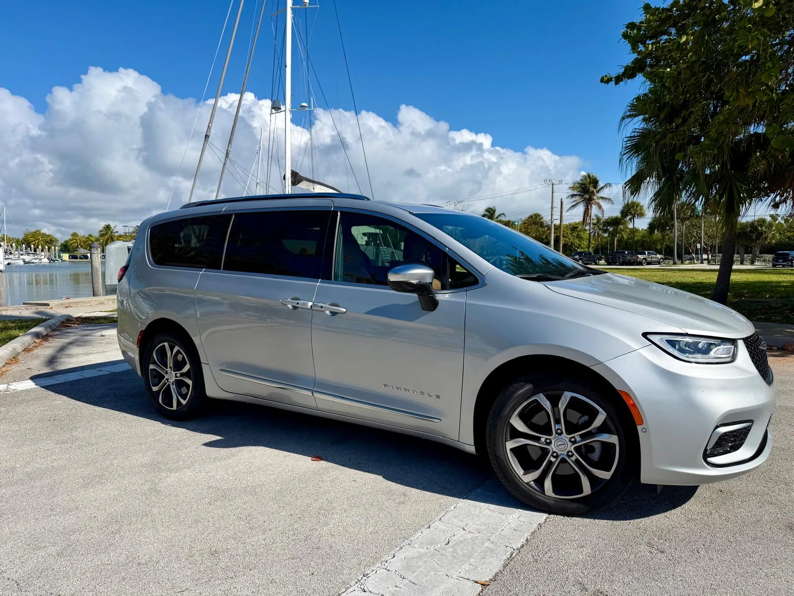 Chrysler Pacifica Pinnacle plateada de perfil, estacionada frente a una marina con veleros