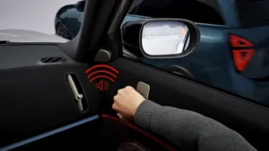 Mano en la manija de la puerta de un MINI con aviso de salida segura por un auto que se acerca