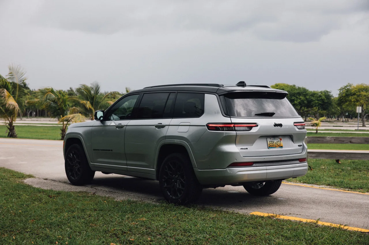 Jeep Grand Cherokee L Summit plateado con techo negro sobre el pasto, vista trasera de tres cuartos