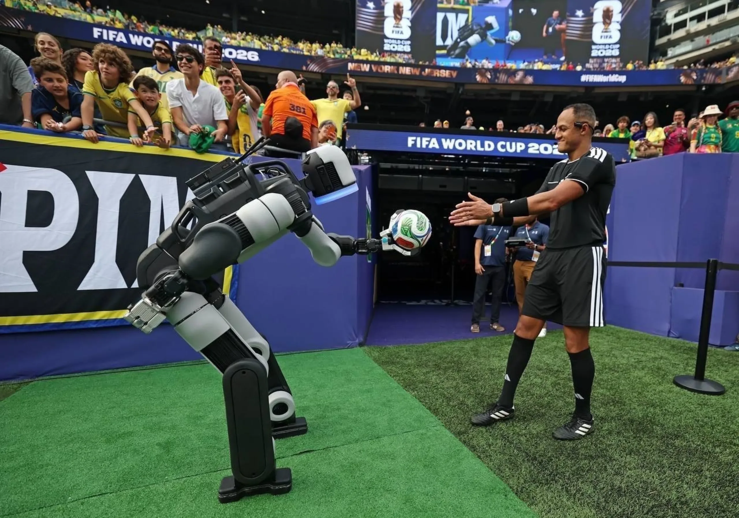 Robot Atlas entrega el balón al árbitro junto al túnel de jugadores en un partido del Mundial 2026