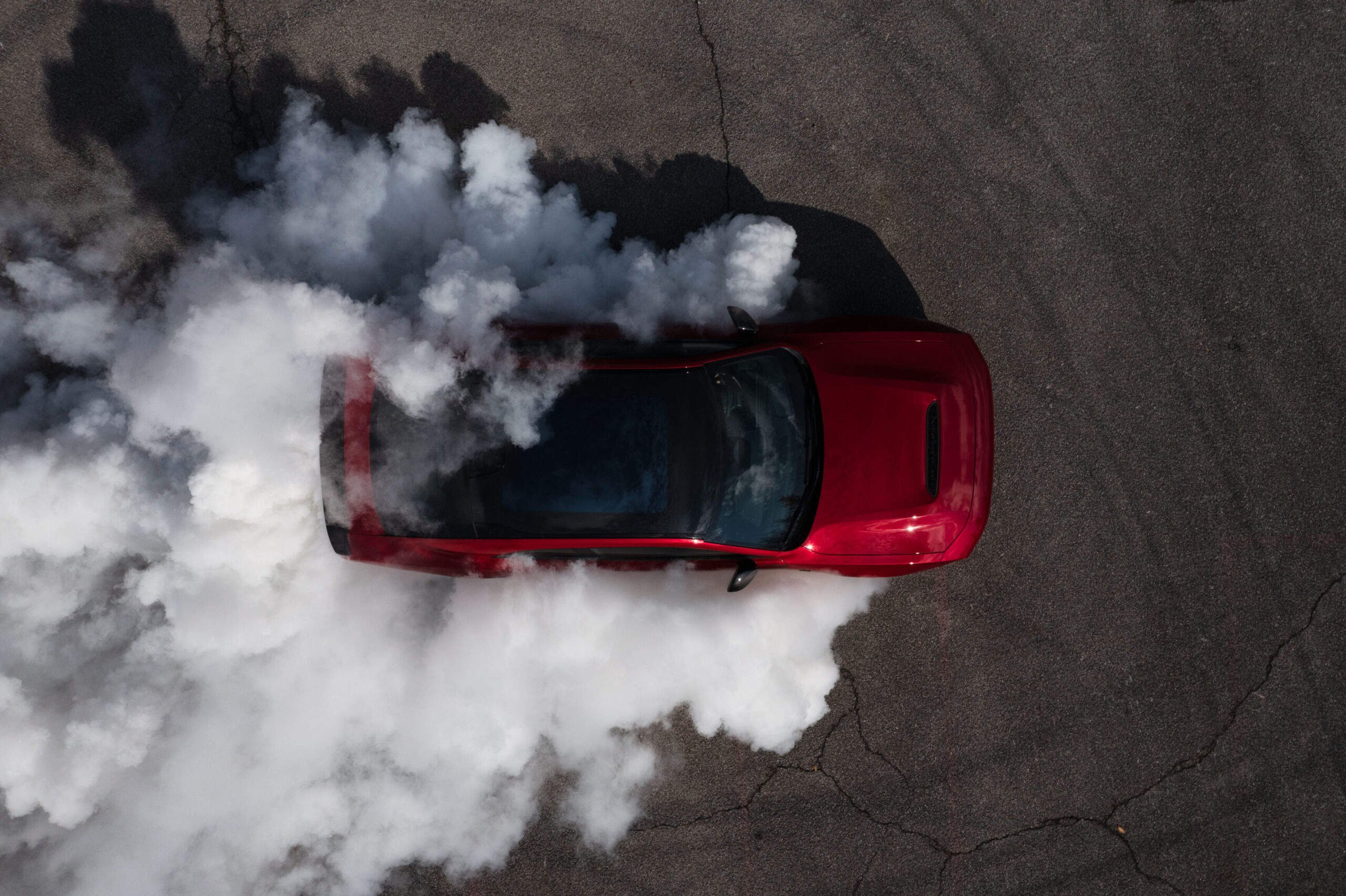 Dodge Charger Hellcat en rumor: un Charger rojo de dos puertas haciendo un burnout, visto desde arriba