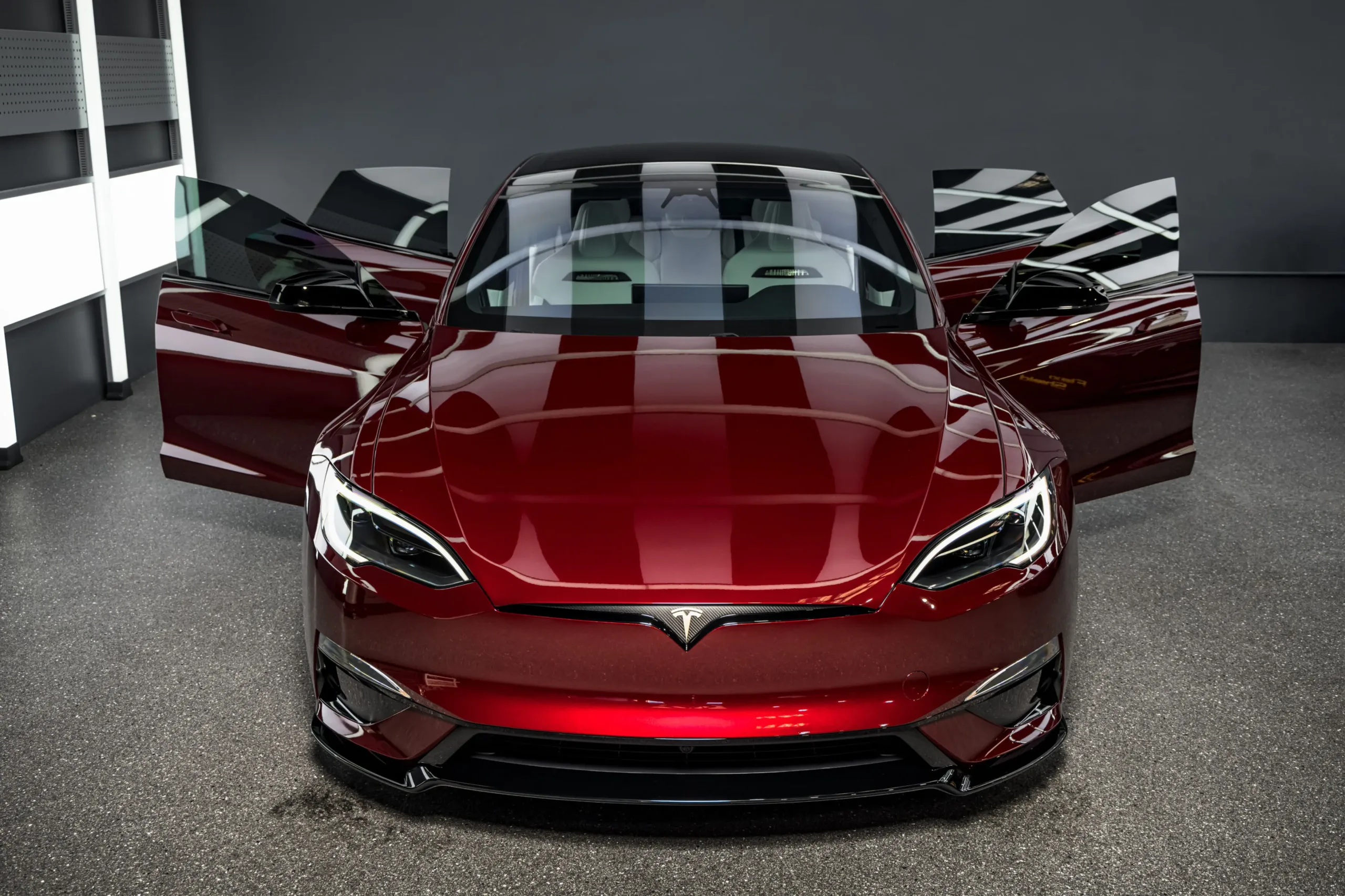 Tesla Model S Plaid Signature Edition #001 rojo con las cuatro puertas abiertas en un taller, vista frontal