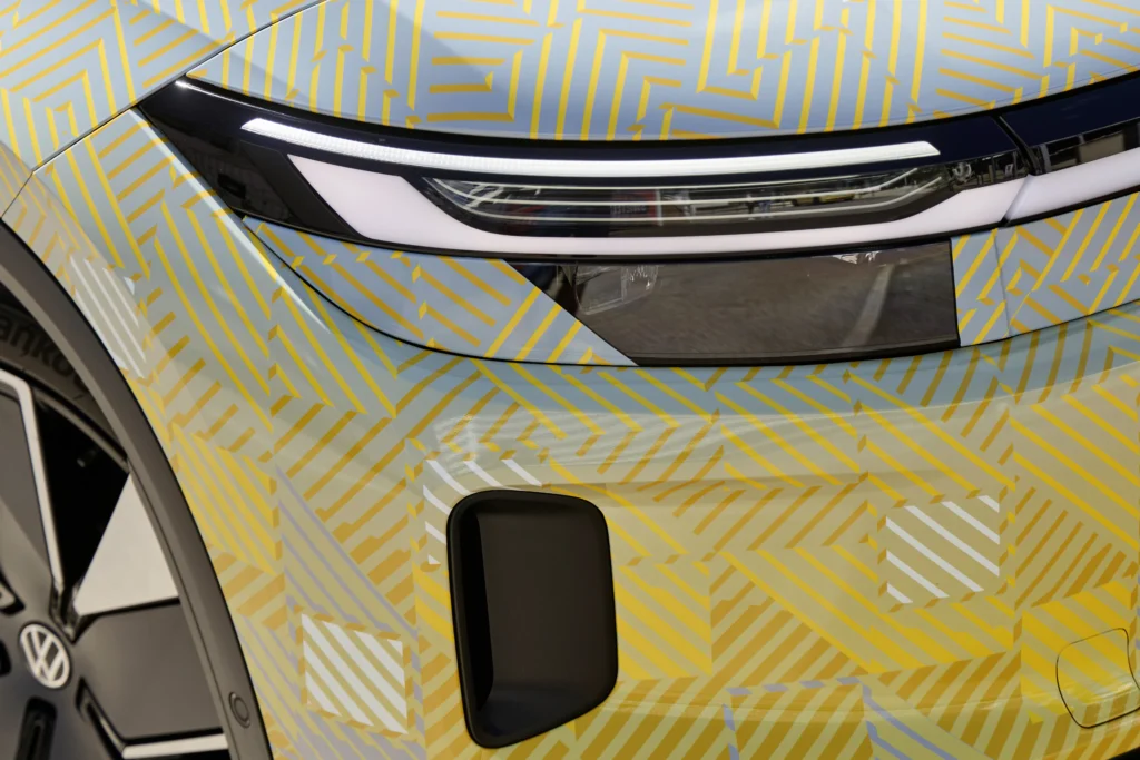 Primer plano del faro delantero y una entrada de aire de un prototipo de Volkswagen camuflado