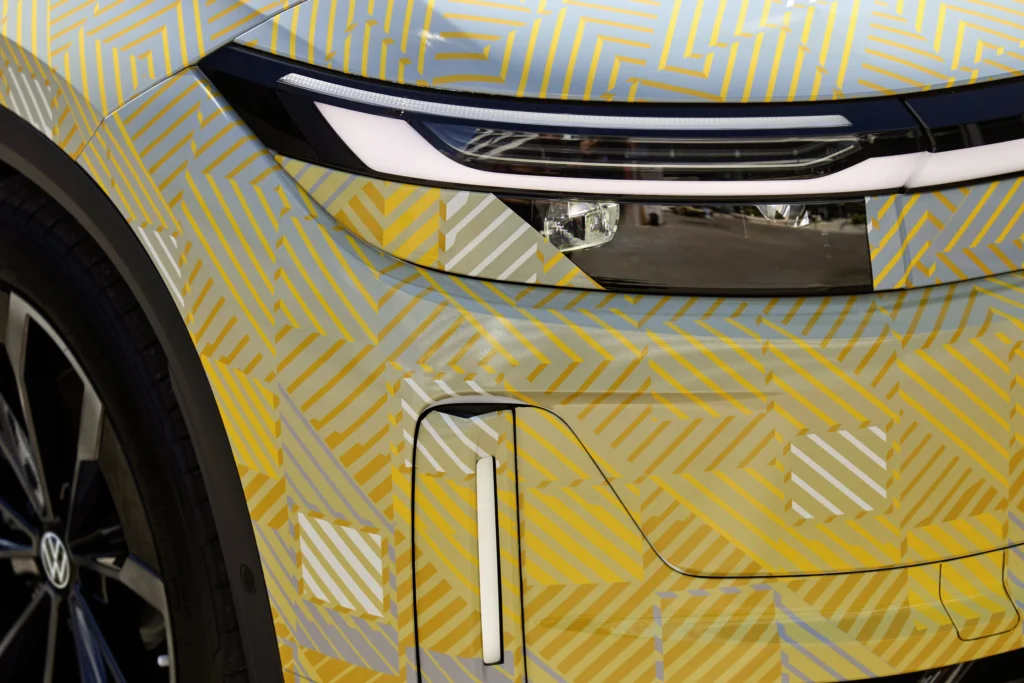 Detalle del faro LED y la toma de aire frontal de un prototipo de Volkswagen con camuflaje de rayas