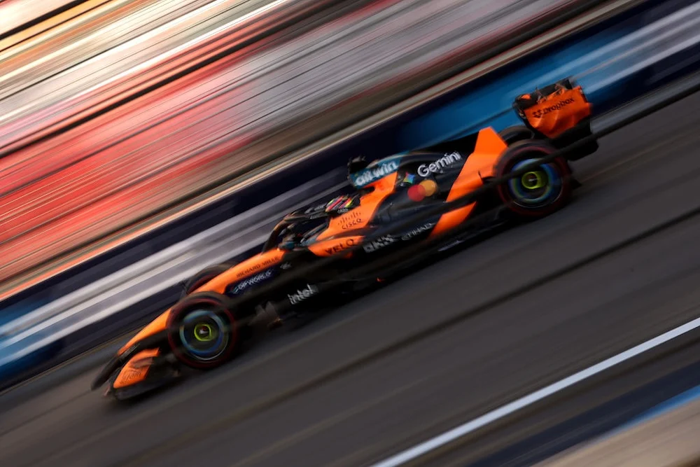 Un McLaren naranja a alta velocidad en el circuito urbano de Bakú, con el fondo barrido por el movimiento