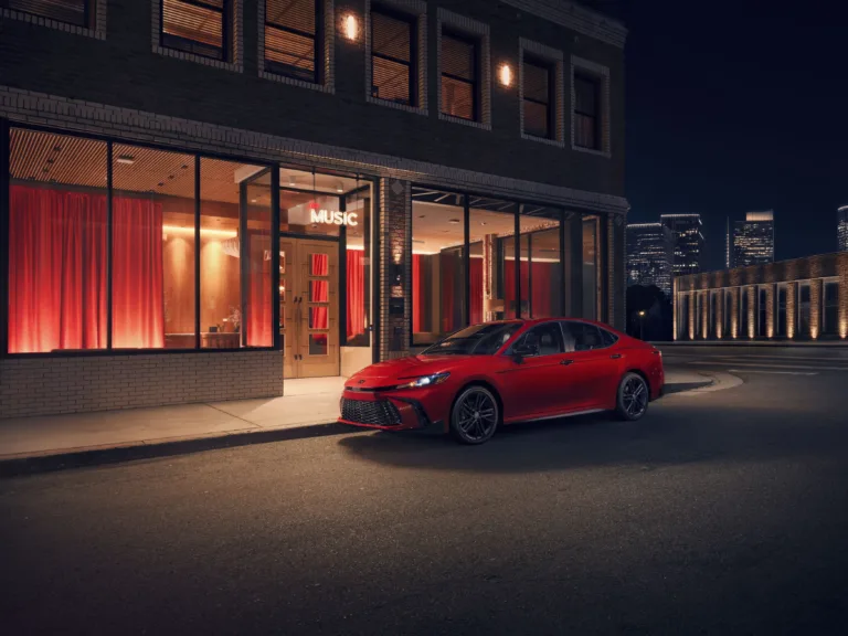 Toyota Camry Nightshade 2027 rojo estacionado de noche frente a un edificio iluminado