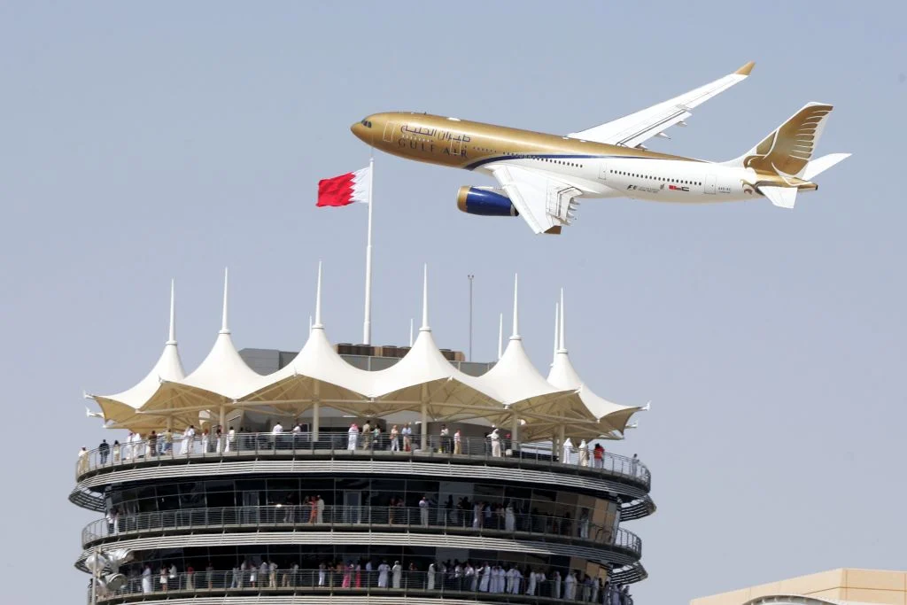 Avión de Gulf Air sobrevuela la torre de tribunas del circuito de Bahréin, con la bandera bahreiní en lo alto