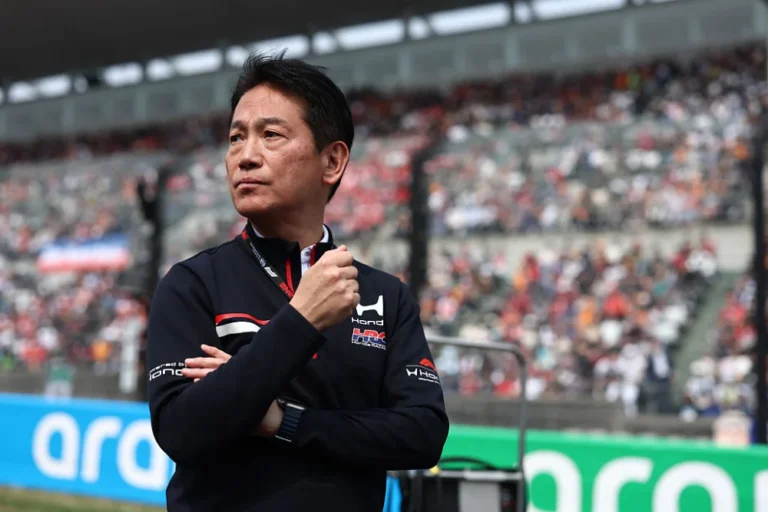 Koji Watanabe, presidente de HRC, con chaqueta negra de Honda y brazos cruzados frente a una tribuna llena