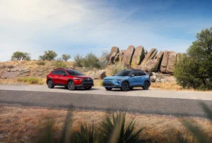 Toyota Corolla Cross 2027 rojo y Corolla Cross Hybrid azul en una carretera junto a grandes rocas