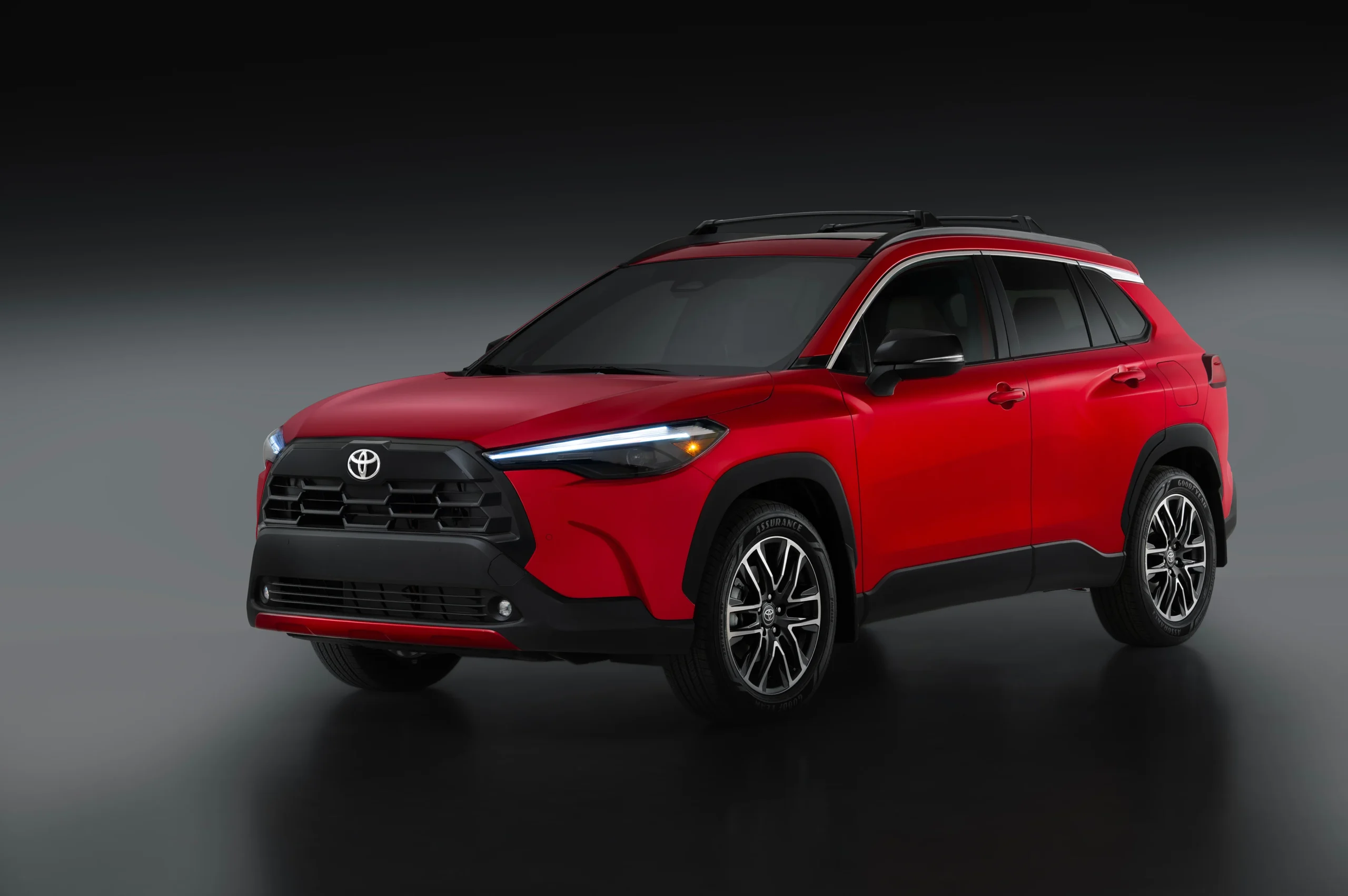 Toyota Corolla Cross de gasolina rojo con techo negro en un estudio, vista de tres cuartos delantera