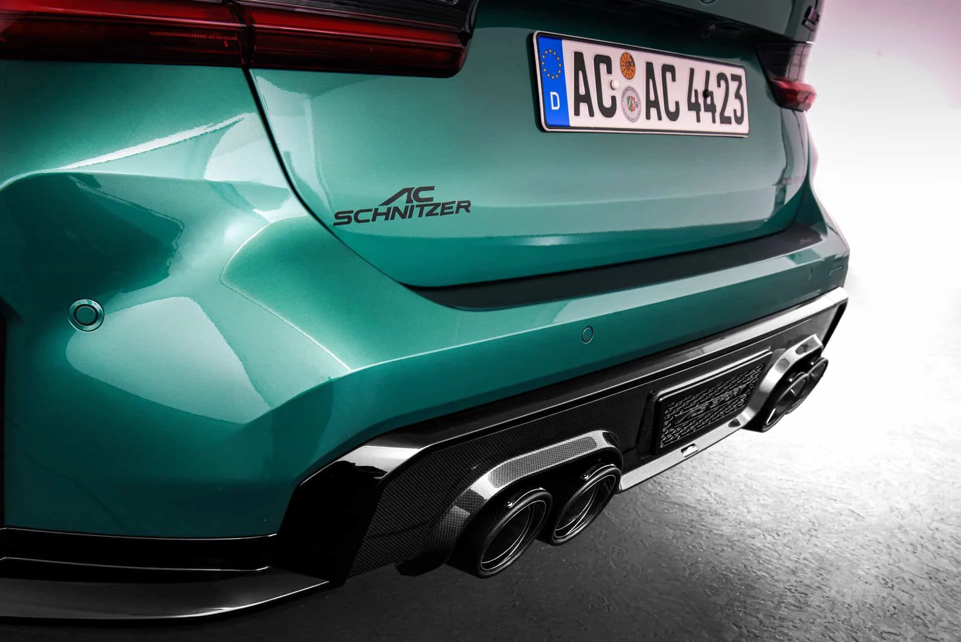 Parte trasera de un BMW M3 Touring verde con difusor y cuatro salidas de escape de carbono de AC Schnitzer