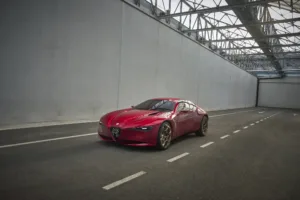 Alfa Romeo Cuorerosso: coupé rojo 2+2 visto de frente en tres cuartos, en una nave con techo de vidrio