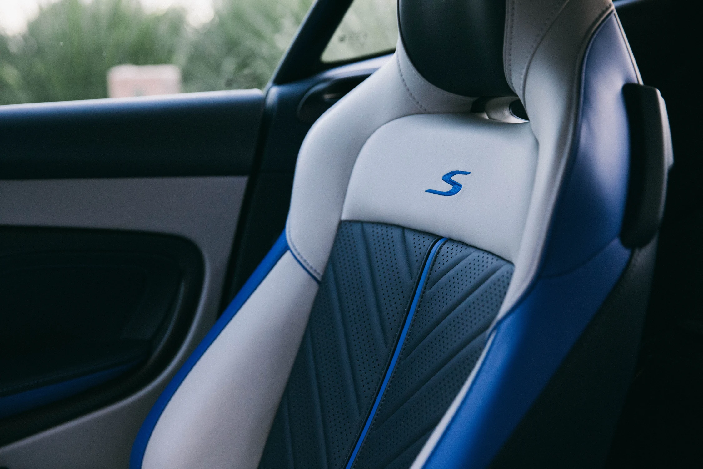 Asiento del Aston Martin DB12 S con cuero blanco y azul, costuras de contraste y la letra S bordada