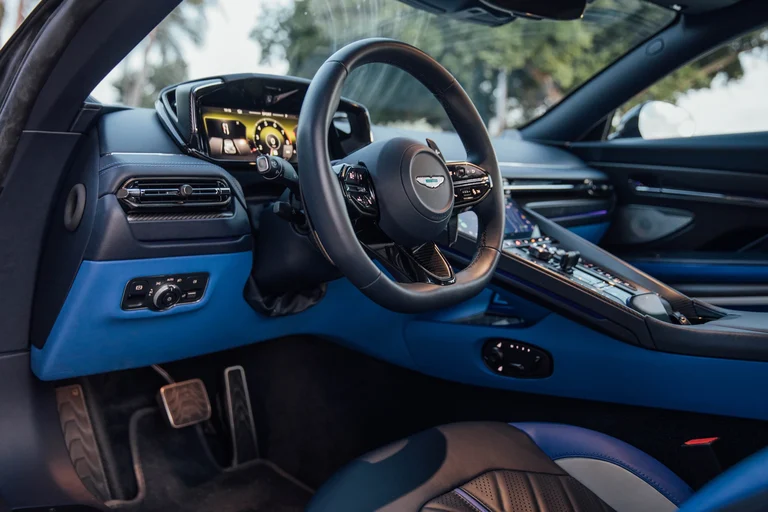 Puesto de conducción del Aston Martin DB12 S con volante, cuadro digital y tablero azul y negro