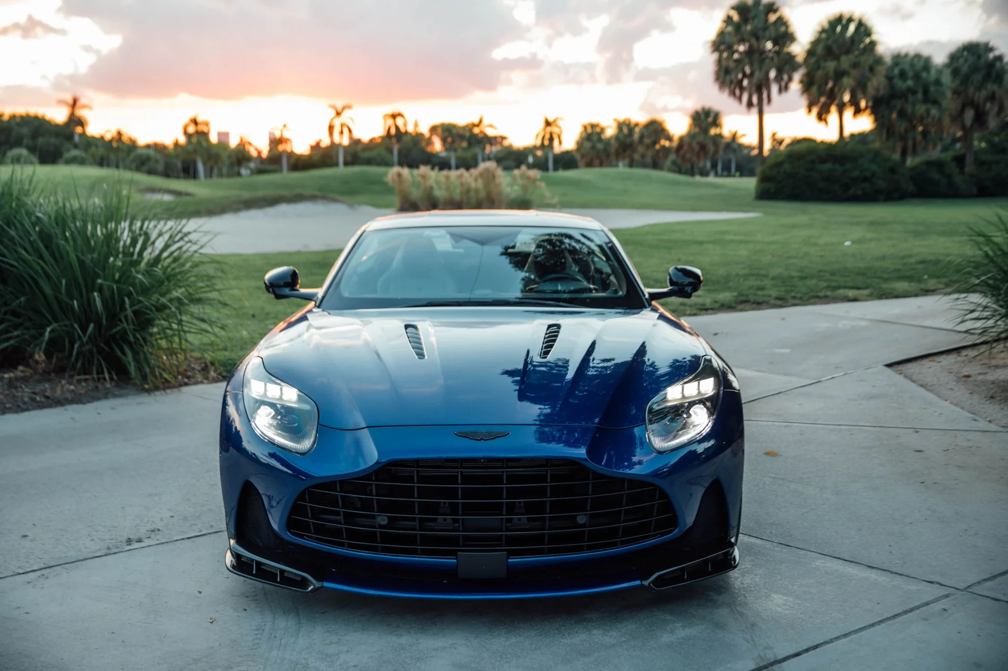 Frente del Aston Martin DB12 S azul con la parrilla grande, el divisor delantero y las aberturas del capó