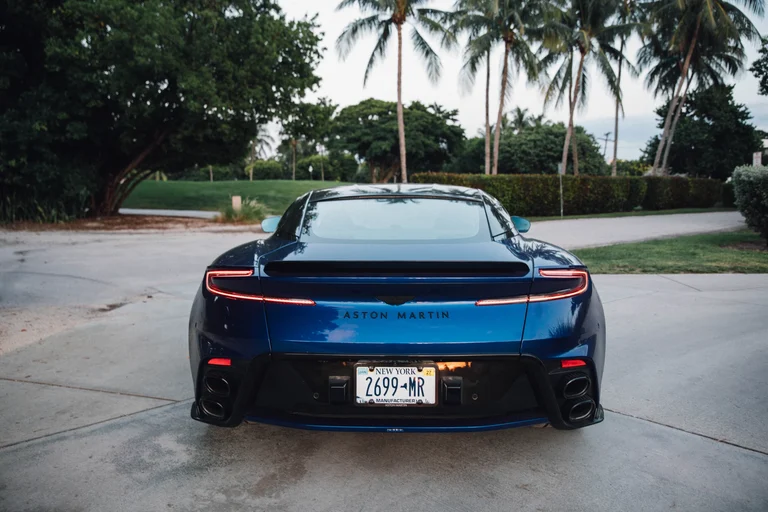 Parte trasera del Aston Martin DB12 S azul vista de frente, con la franja de luz y las salidas de escape
