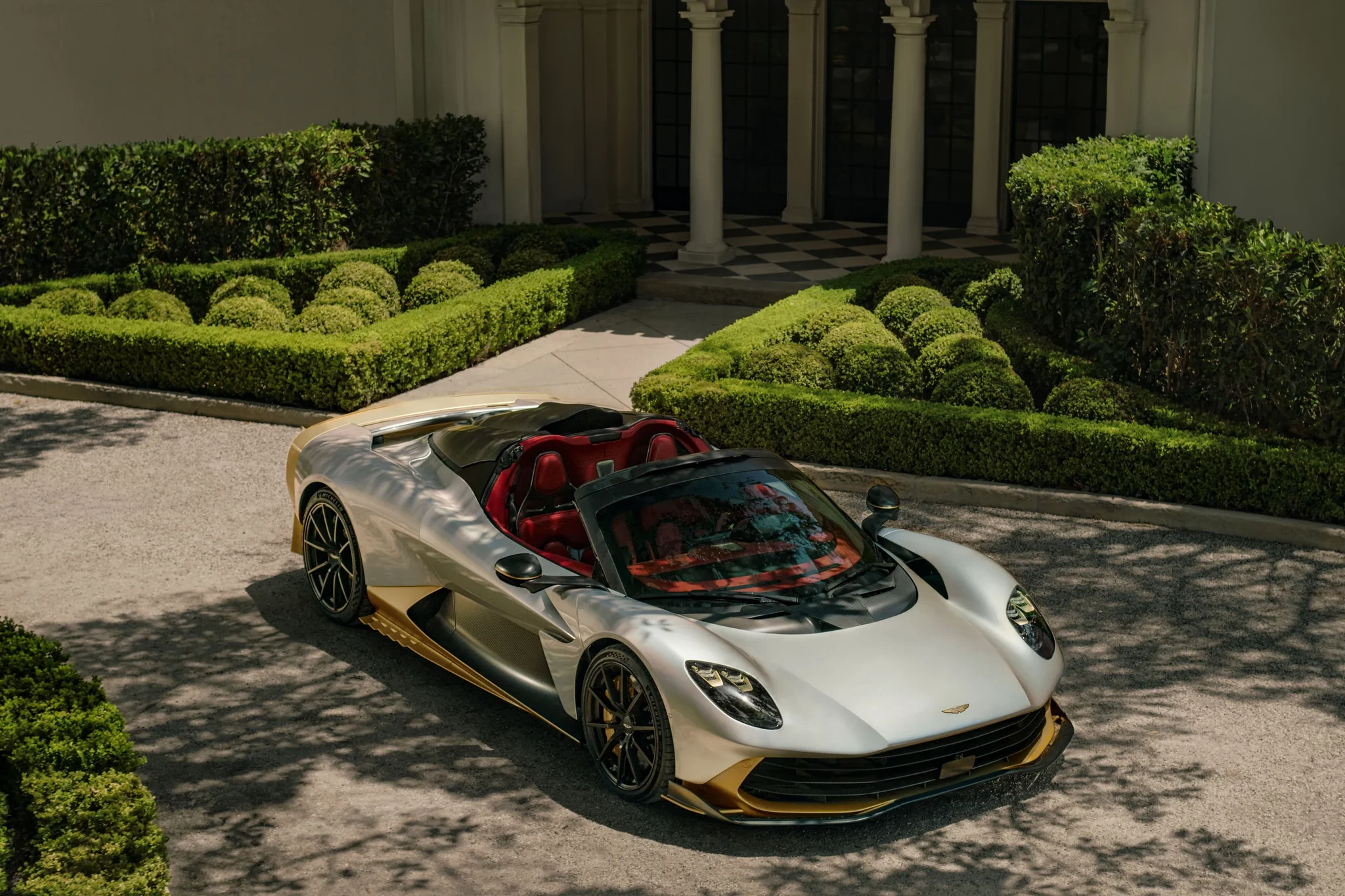 Aston Martin Valhalla Spider de tres cuartos frontales, visto desde arriba, en un camino de grava con setos
