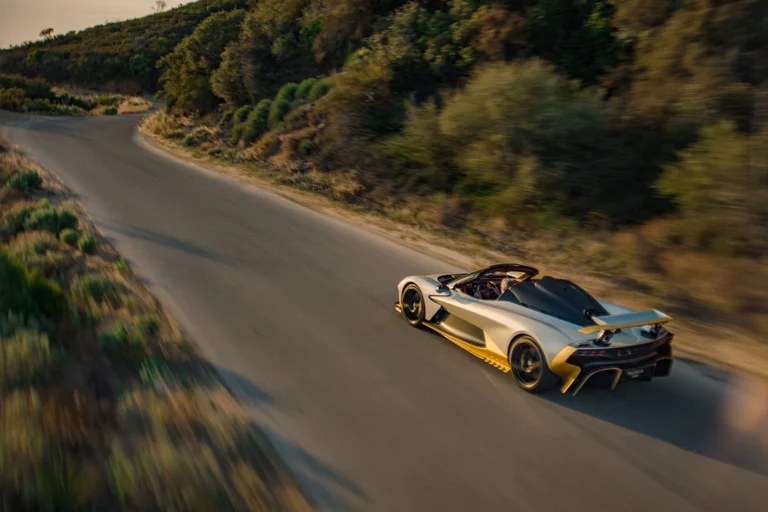 Aston Martin Valhalla Spider visto de lejos y desde atrás en una carretera sinuosa de montaña