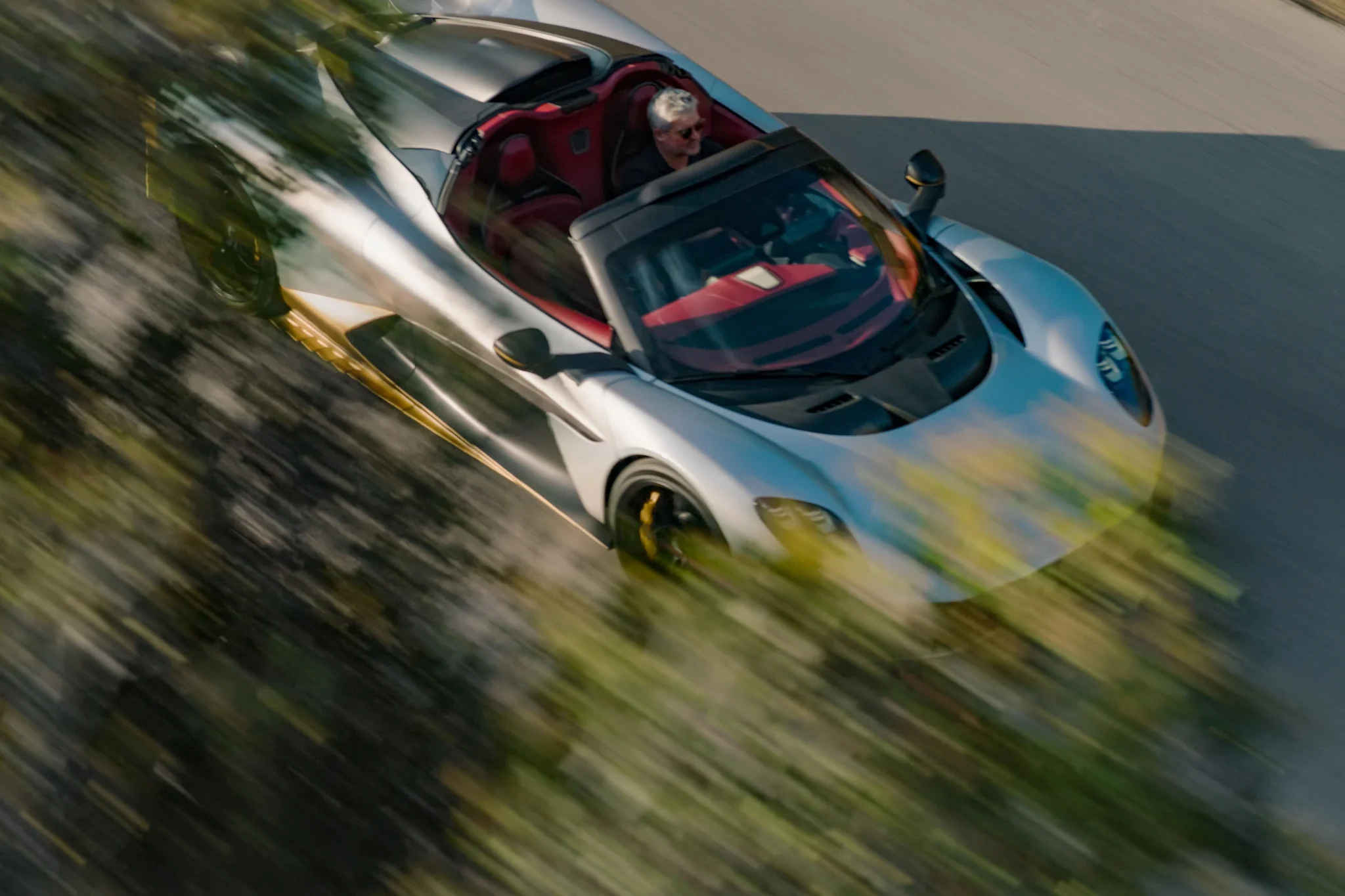 Aston Martin Valhalla Spider visto desde arriba y en movimiento, con el conductor y el interior rojo a la vista