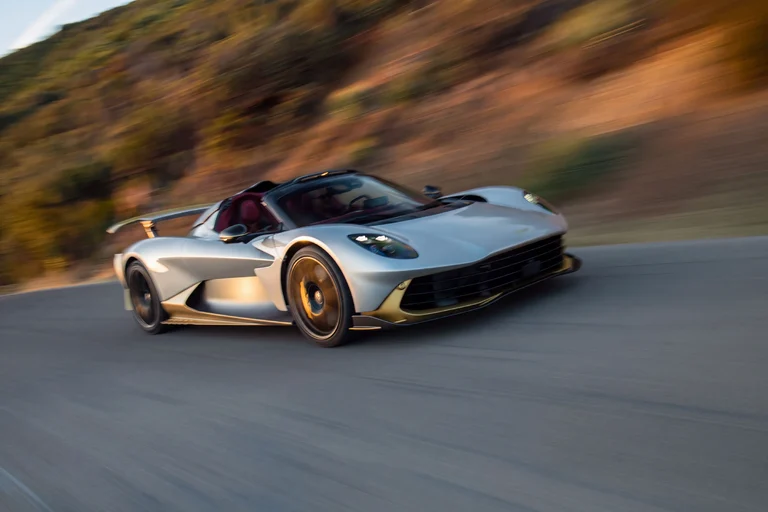 Aston Martin Valhalla Spider en movimiento por una carretera de montaña, visto de lado y de frente