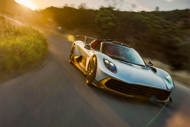 Aston Martin Valhalla Spider de tres cuartos frontales en una curva, con luz dorada y la vegetación borrosa