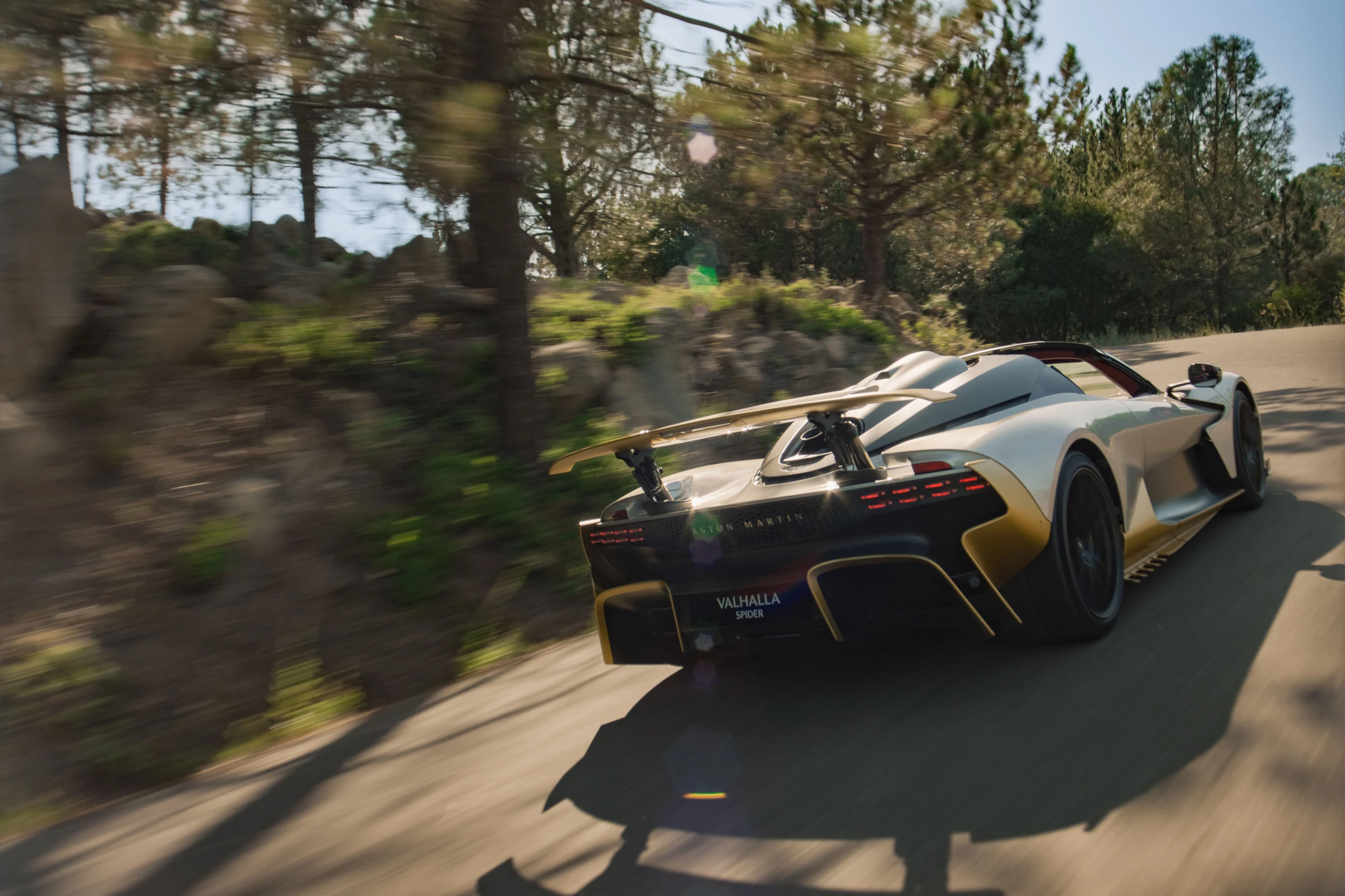 Parte trasera del Aston Martin Valhalla Spider en una curva de carretera, con el alerón activo levantado