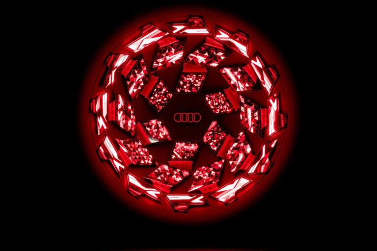 Luz OLED circular de Audi con el logo de los cuatro aros en el centro, encendida en rojo sobre fondo negro