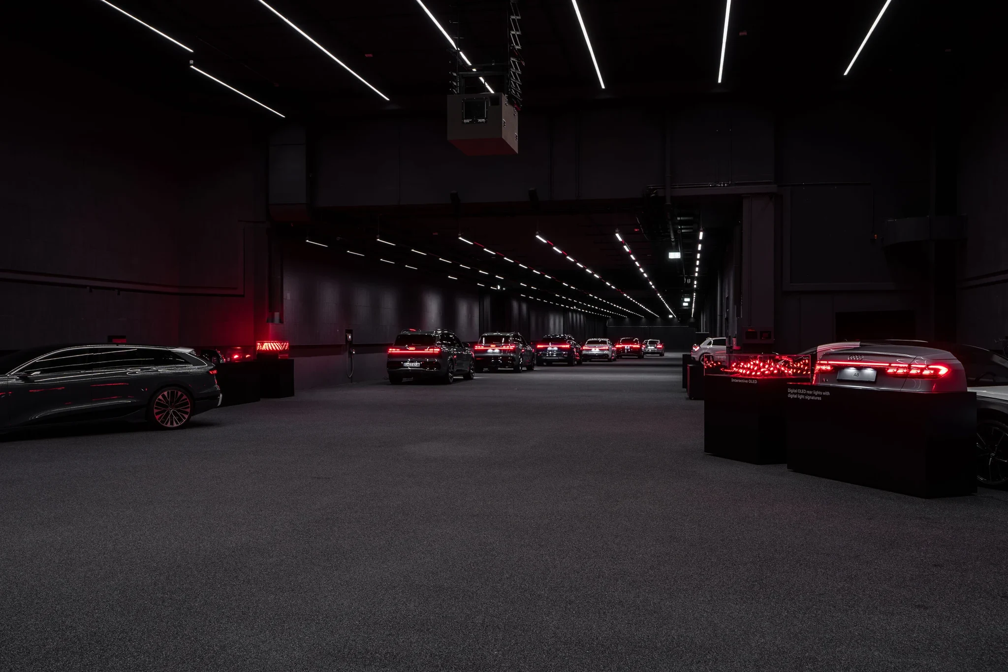 Sala de exhibición de Audi con luces traseras digitales OLED encendidas en rojo sobre soportes oscuros
