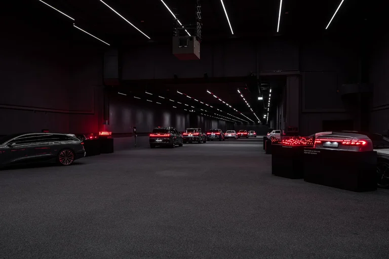 Sala de exhibición de Audi con luces traseras digitales OLED encendidas en rojo sobre soportes oscuros