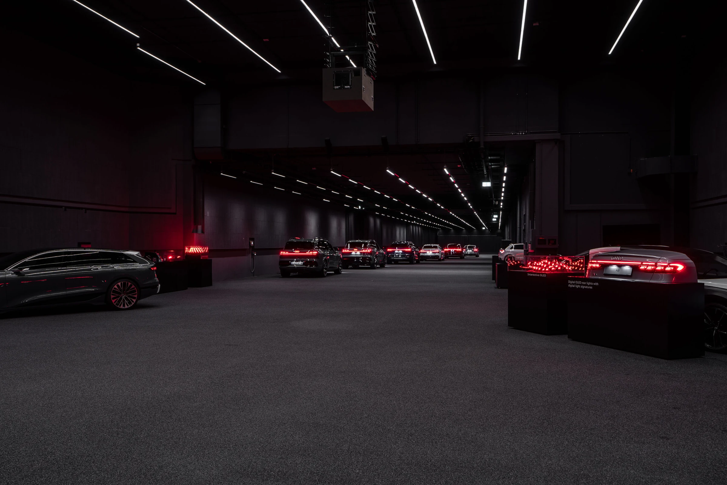 Sala de exhibición de Audi con luces traseras digitales OLED encendidas en rojo sobre soportes oscuros