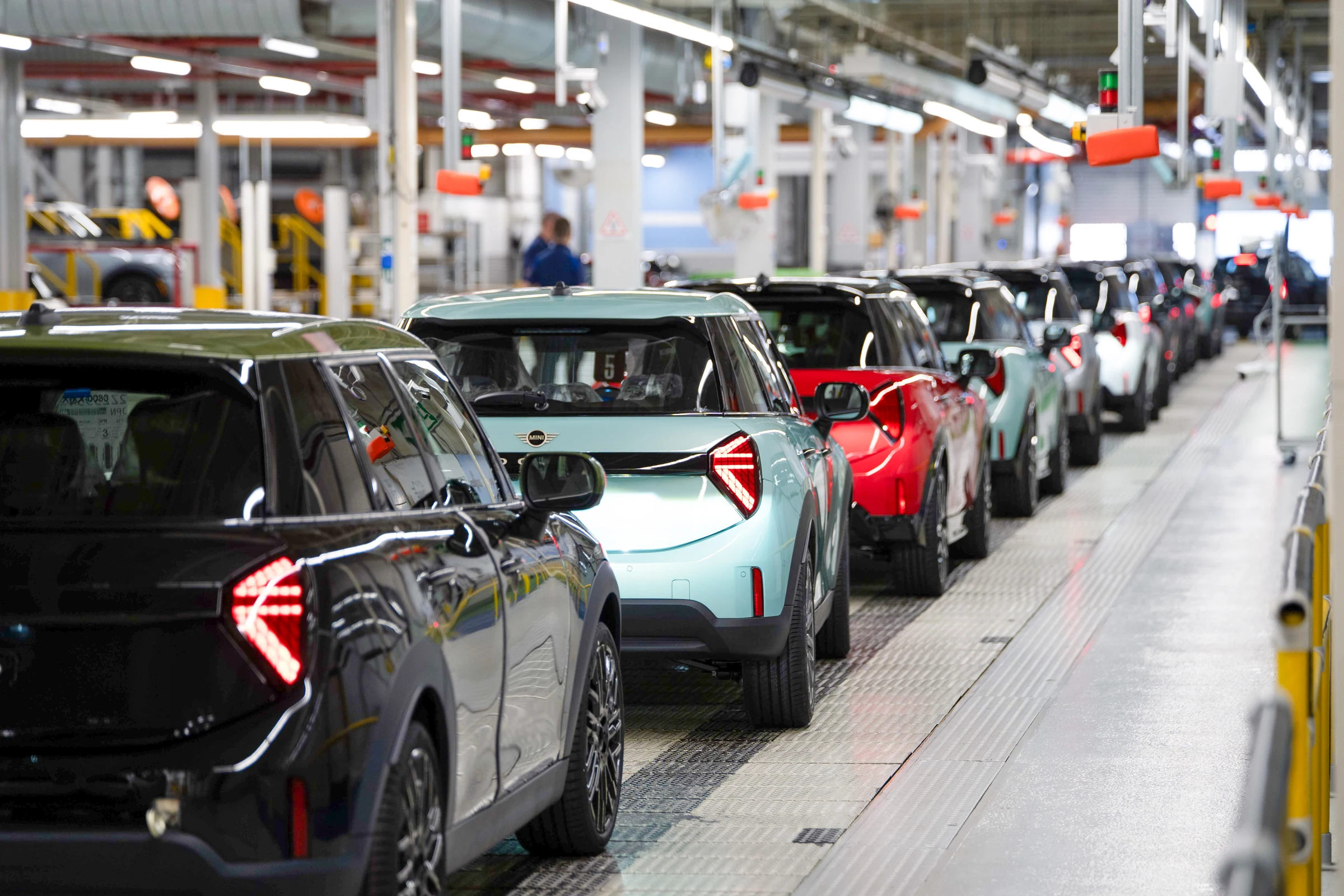 Fila de MINI recién fabricados, negro, verde agua y rojo, en un pasillo de la planta de Oxford