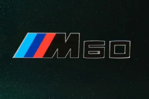 Emblema M60 con las franjas de color de BMW M sobre fondo oscuro