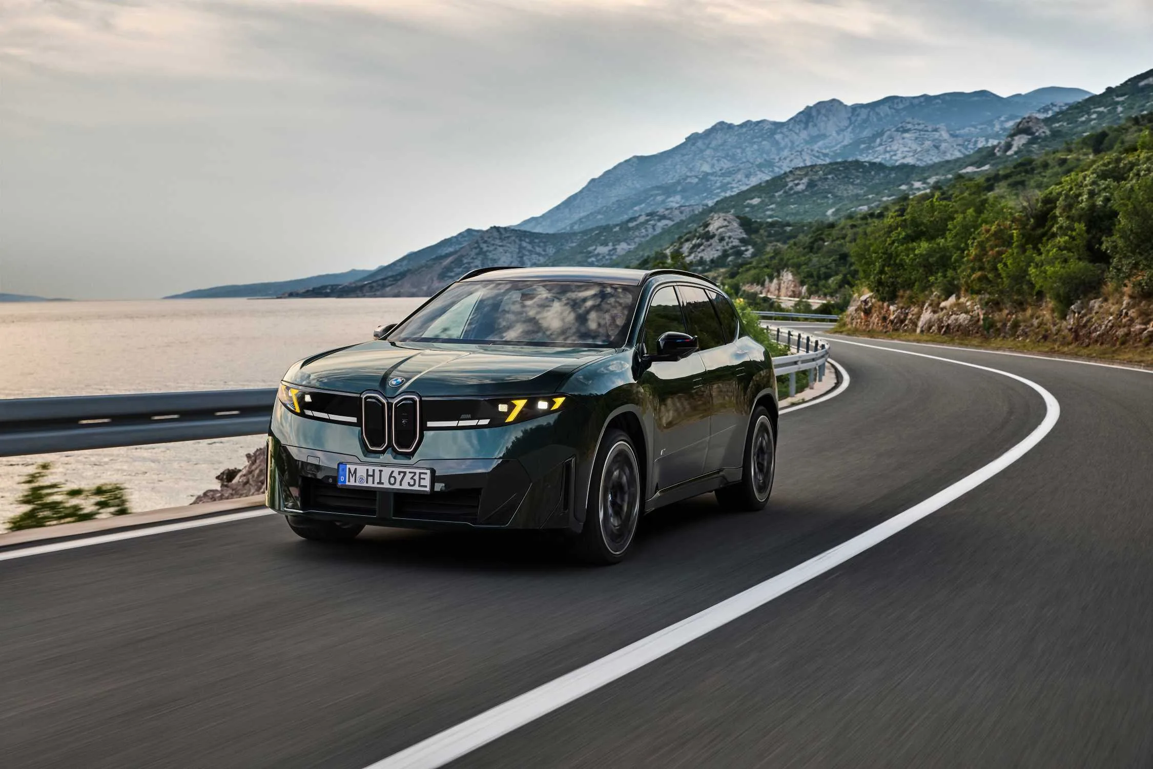 BMW iX3 M60 xDrive en una carretera costera, vista frontal tres cuartos con luces M Yellow