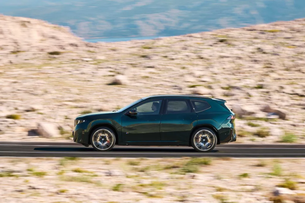 Perfil del BMW iX3 M60 xDrive en movimiento sobre una carretera, con batalla larga y voladizos cortos