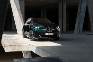 BMW iX3 M60 xDrive sobre una plataforma de concreto entre columnas inclinadas, vista frontal tres cuartos