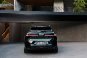 Parte trasera del BMW iX3 M60 xDrive en un garaje de concreto con las luces traseras encendidas