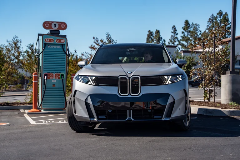 BMW iX5 gris visto de frente junto a un cargador ultrarrápido de IONNA, en California