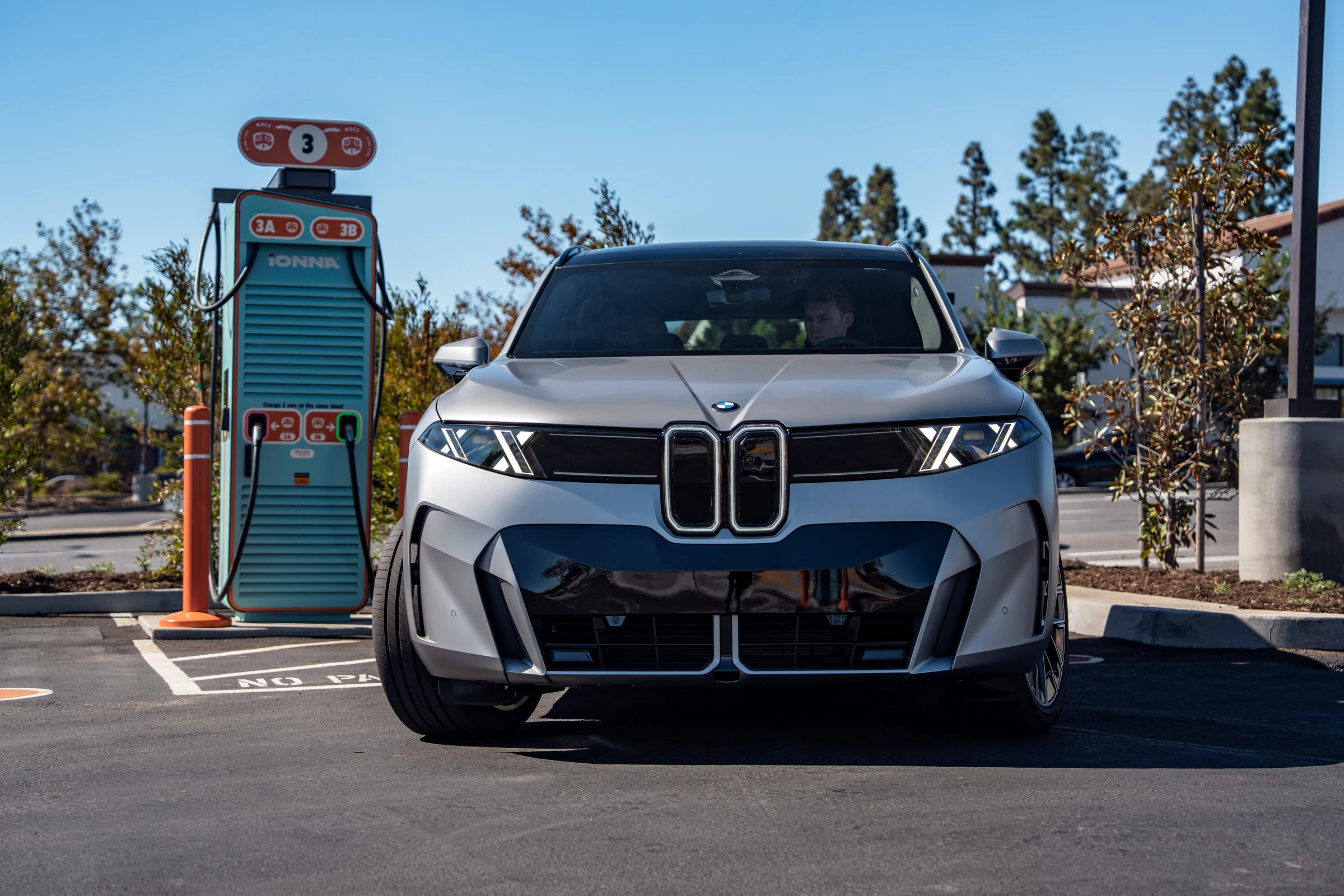 BMW iX5 gris visto de frente junto a un cargador ultrarrápido de IONNA, en California
