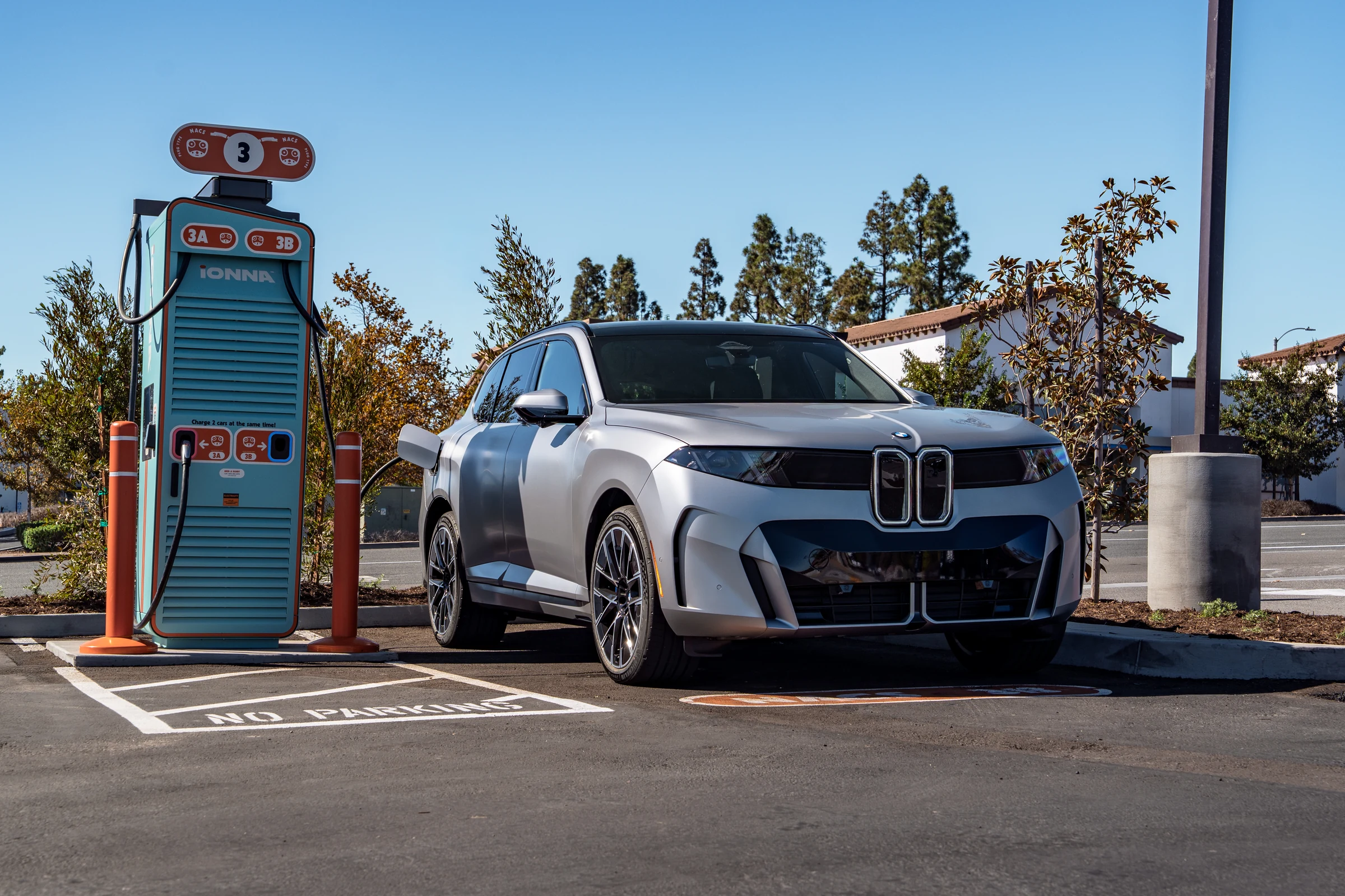 BMW iX5 con carga de 460 kW: el SUV eléctrico visto en tres cuartos, estacionado junto al cargador