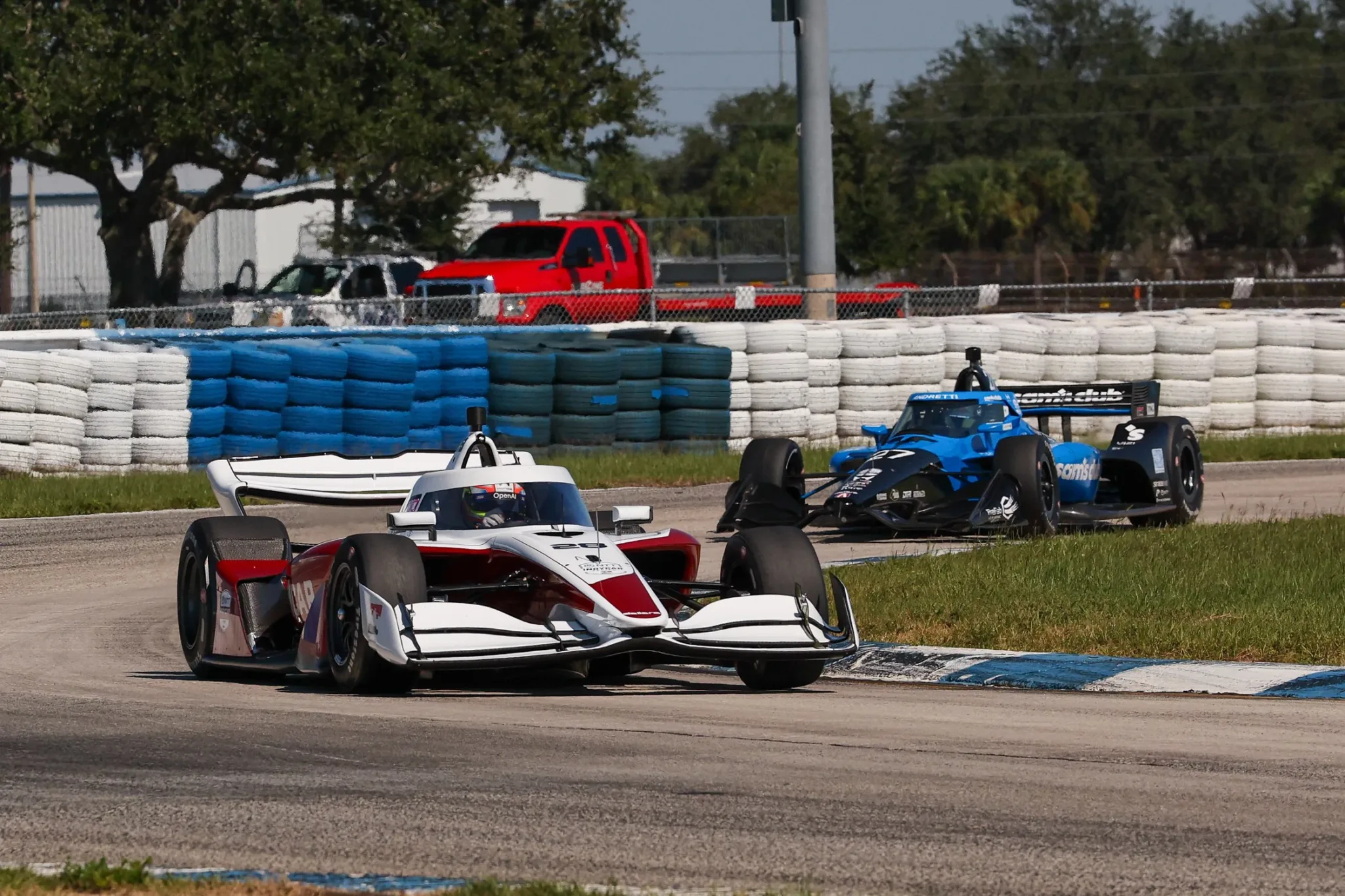 Dallara IR28 de la IndyCar en pista junto a otro monoplaza azul en Sebring