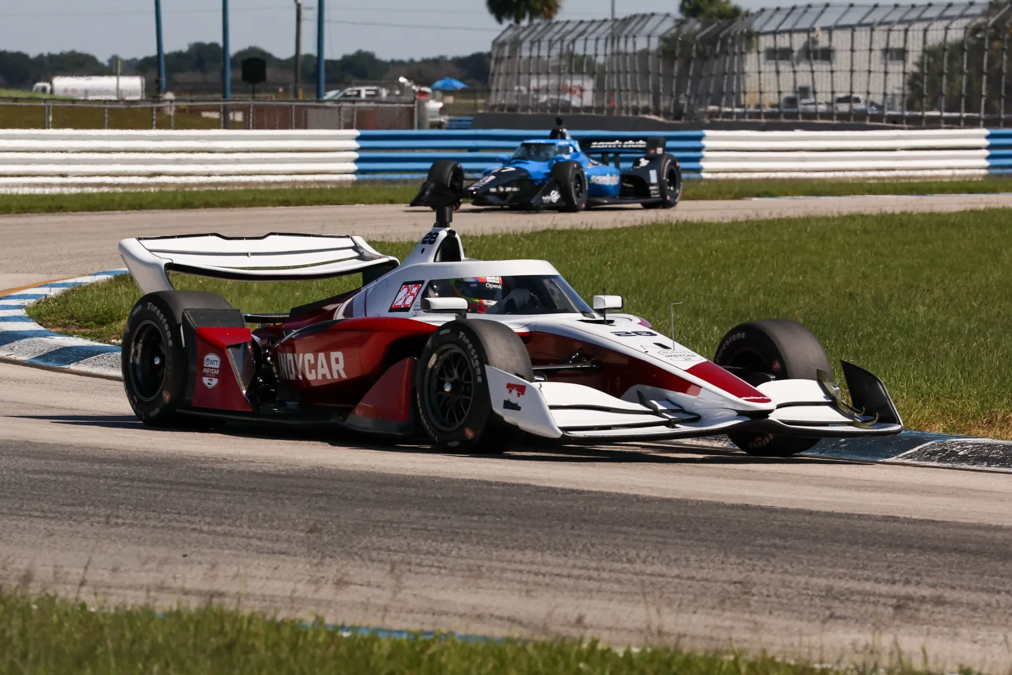 Dallara IR28 rojo y blanco tomando una curva de Sebring con otro monoplaza al fondo