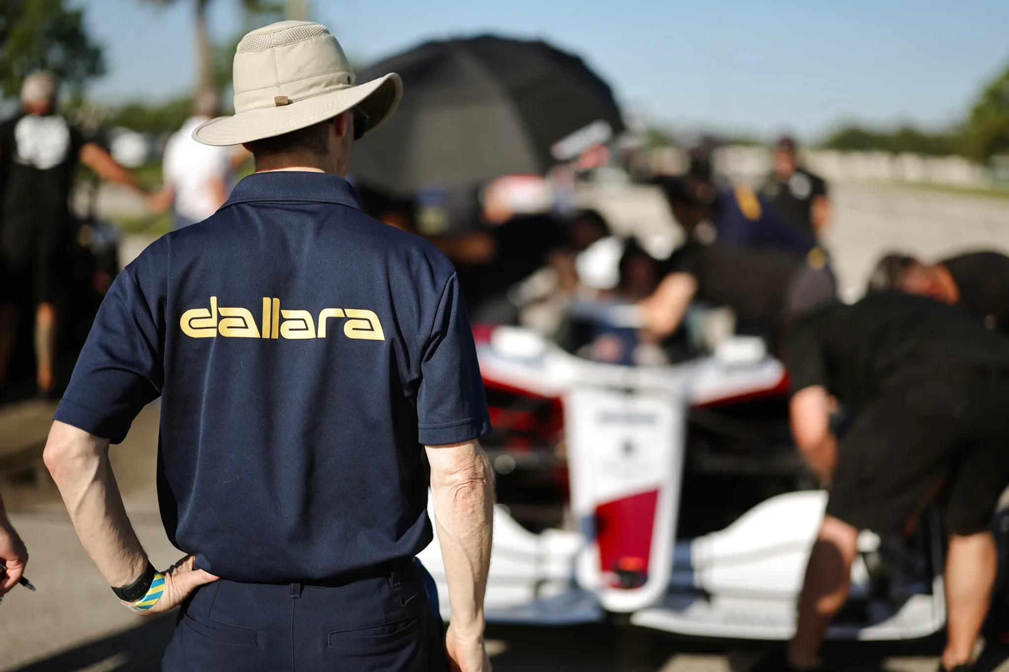 Integrante de Dallara con sombrero observando la preparación del monoplaza IR28 en boxes