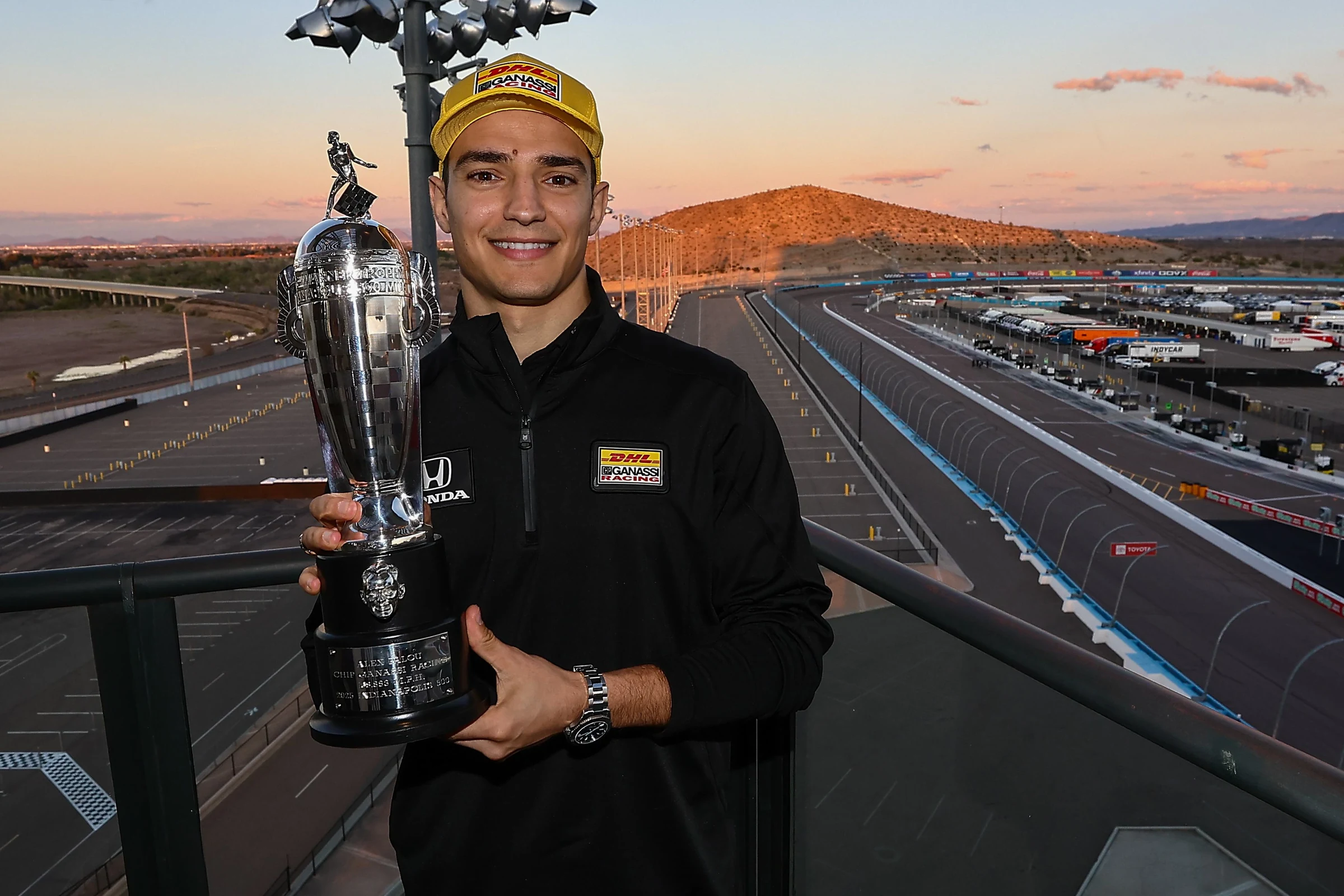 Álex Palou sonríe con la gorra de Chip Ganassi Racing y la réplica del trofeo Borg-Warner junto a la pista de Phoenix