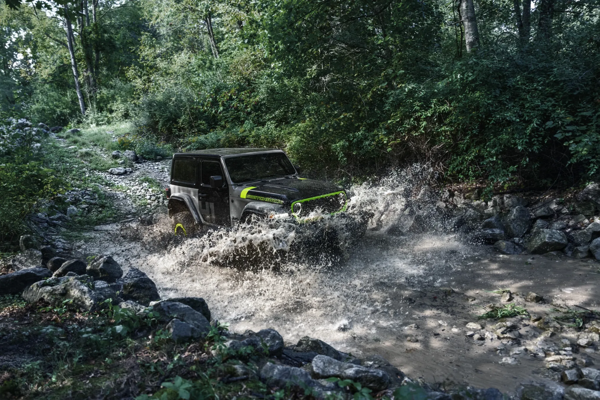 Jeep Wrangler Switchback cruzando un río de aguas bajas entre rocas