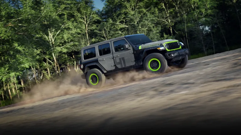 Jeep Wrangler Switchback en movimiento sobre un camino de tierra, con capó y puertas de colores distintos