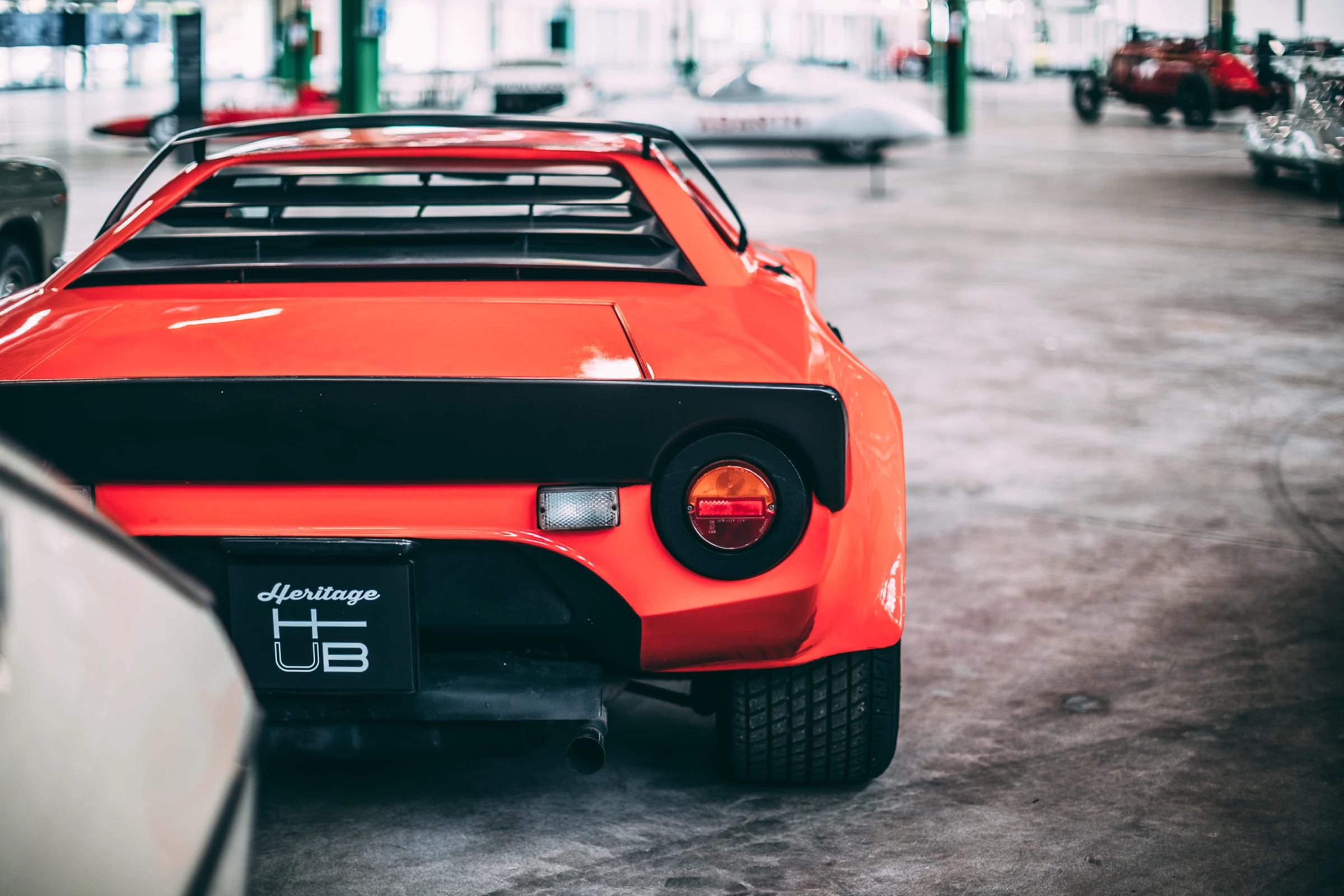 Parte trasera de un Lancia Stratos naranja en el Heritage Hub, con la placa de Heritage Hub