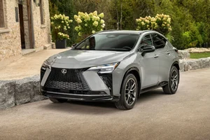 Lexus NX 2027 350h F SPORT en color gris Incognito, visto de frente en tres cuartos, frente a un edificio de piedra